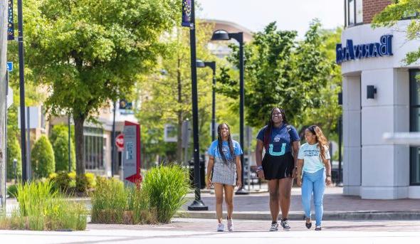 three female students wearing odu apparel are walking on monarch way
