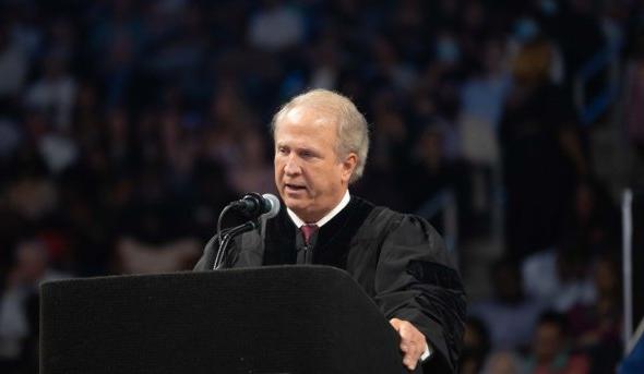 Man speaking behind a podium at a commencement ceremony