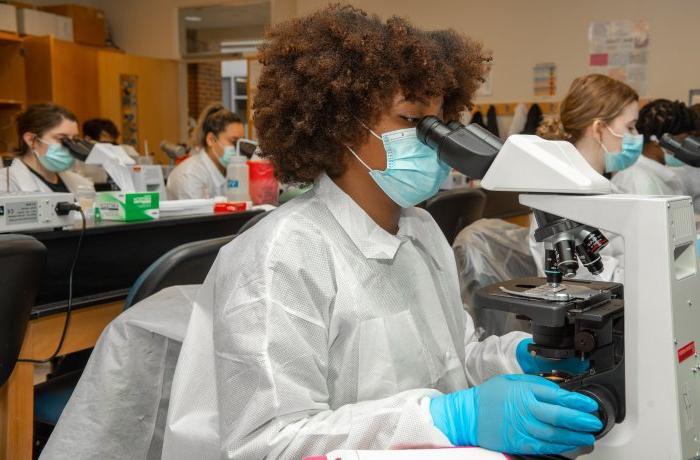Student in medical laboratory looks into microscope
