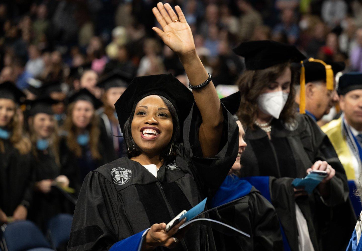 an odu doctoral student waves to the crowd with a diploma in her hand
