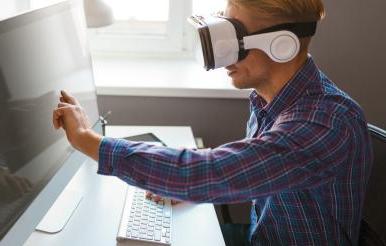 戴着VR眼镜的人触摸着电脑显示器