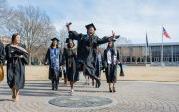 A student jumps in the air while walking across the ODU seal.