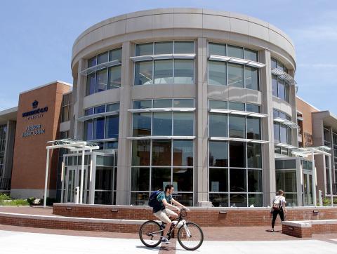 Student riding a bike in front of Broderick Dining Commons